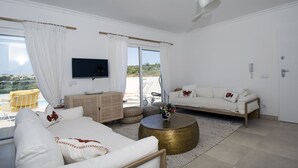 Een moderne woonkamer met een bank, een salontafel en een aan de muur bevestigde televisie.