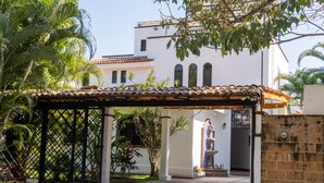 Un espacio de patio techado con techo de baldosas, pared de piedra y una reja.