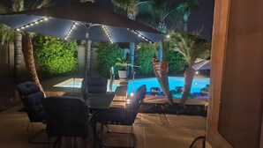 An outdoor patio with a table and chairs, a pool, and palm trees. - "Cactus Cooler Casita" Private Pool and Heated Spa Included Large walk-in Shower (Queen Creek)