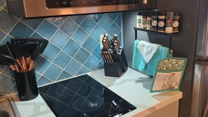 A kitchen with a black induction cooktop, a knife block, a spice rack, and a decorative kitchen towel. - "Cactus Cooler Casita" Private Pool and Heated Spa Included Large walk-in Shower (Queen Creek)
