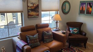 A living room with a brown leather sofa and armchair, patterned cushions, a side table with a lamp, and desert-themed artwork on the walls. - "Cactus Cooler Casita" Private Pool and Heated Spa Included Large walk-in Shower (Queen Creek)