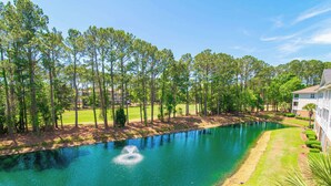 Un parcours de golf avec un étang, entouré d’arbres et bordé d’un bâtiment.