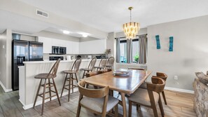 Una cocina moderna con una isla central, sillas de madera y una lámpara de araña.