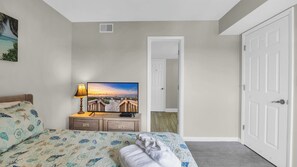 Un dormitorio con cama, televisión, lámpara y puerta.