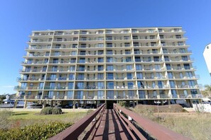 Un hotel de varios pisos con balcones, un paseo central y un cielo despejado.