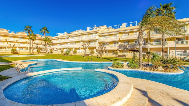 A resort with a large swimming pool, palm trees, and a multi-story building with balconies. - Beautiful apartment in Santa Pola (Santa Pola)