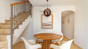 A dining area with a wooden table and white chairs, a staircase with metal railings, and a modern pendant light. - Beautiful apartment in Santa Pola (Santa Pola)