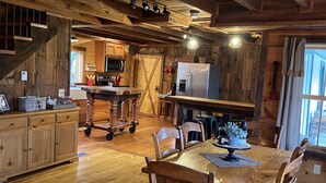 A rustic wooden interior with a dining area, kitchen, and a staircase.
