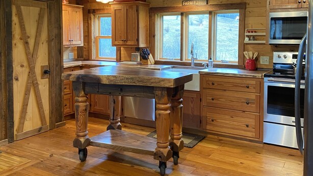 A rustic kitchen with wooden cabinets, a large island, and modern appliances.