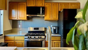 A kitchen with wooden cabinets, a stainless steel stove, a microwave, and a refrigerator. - By Popular Demand - Richmond (Richmond)