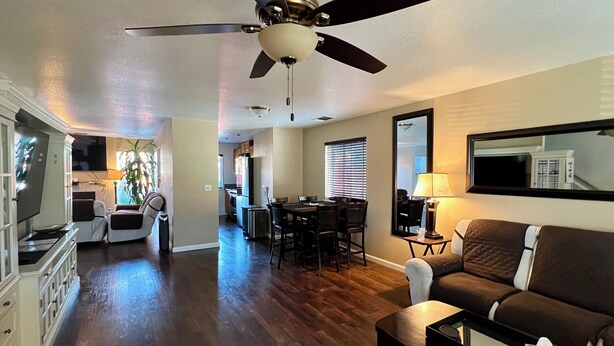 A spacious living area with a ceiling fan, a dining table with chairs, a kitchen area, and a seating area with a couch and a coffee table. - By Popular Demand - Richmond (Richmond)