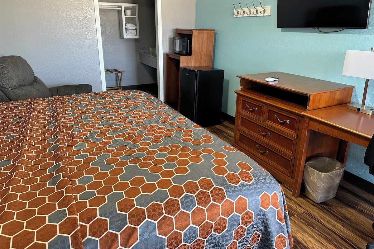 A hotel room with a bed, a desk, a television, and a wardrobe.