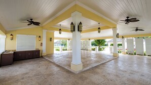 A spacious covered patio with white columns, ceiling fans, and hanging lanterns. - 5min Walk from Love beach | Spacious Home in Nassau (Nassau)