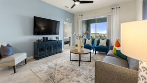 A living room with a flat-screen TV, a ceiling fan, a coffee table, and a sofa. - Lake View At Storey Lake By Shine Villas #703 2 Bedroom Apts (Kissimmee)