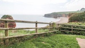 A coastal landscape with a wooden fence, grassy area, and cliffs. - The Retreat (Budleigh Salterton)