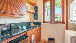 A compact kitchen with a built-in oven, a sink, and wooden cabinets. - Bungallow 2 People Private Pool and Garden (Punta Cana)