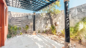 Relax in a serene outdoor space surrounded by lush greenery and a wooden pergola.
