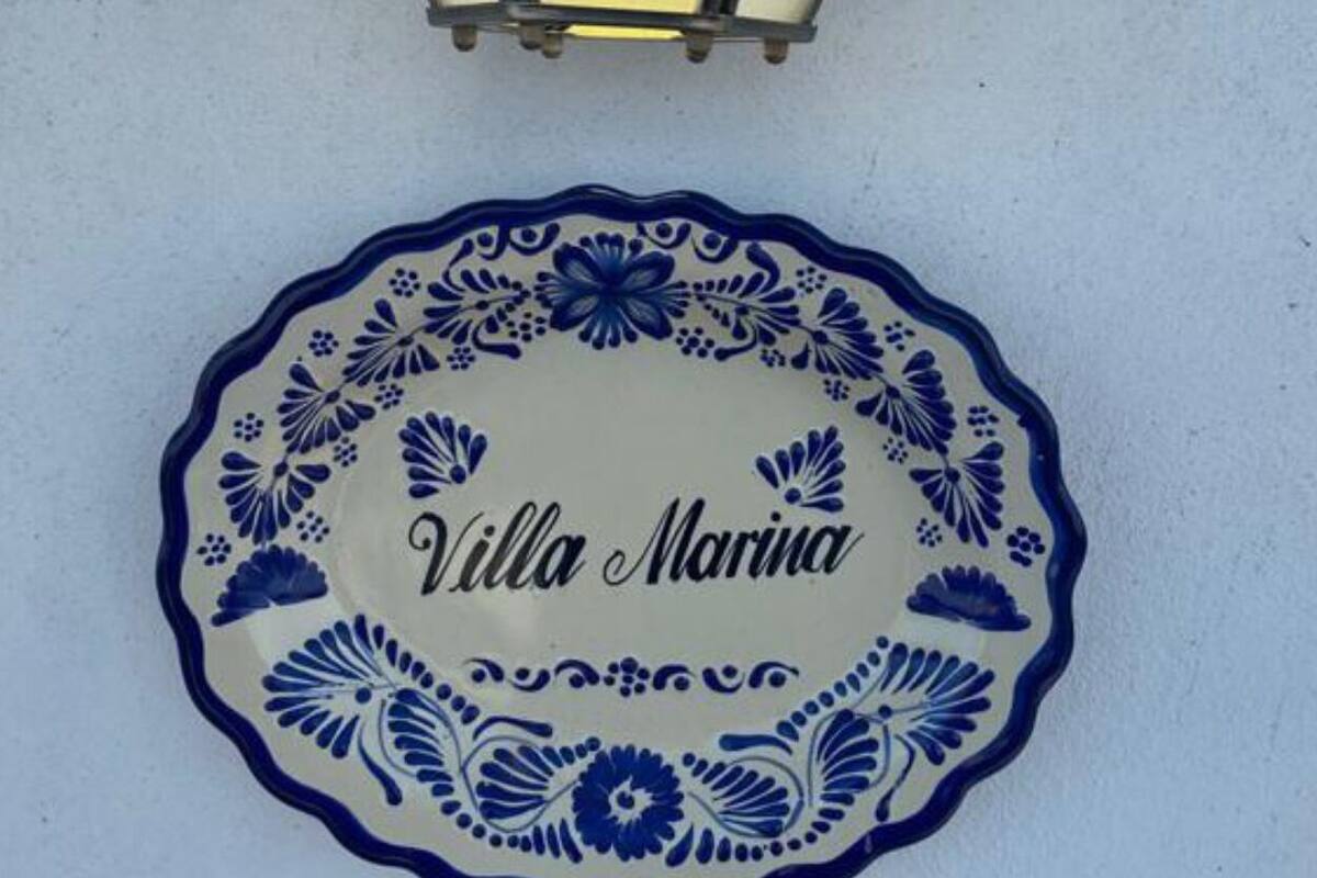 Een aan de muur bevestigde lantaarn en een decoratief bord met daarop 'Villa Marina'.