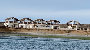 Une propriété située en bord de mer, composée de plusieurs bâtiments dotés de toits de chaume et de murs blancs.