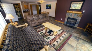 A living room with a sofa, a coffee table, a fireplace, and a dining area. - Rocky Mountain Retreat 1A- 4 bedroom/3 bath with personal hot tub offers Panoramic Mountain Views 4 Cabin (Estes Park)
