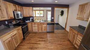 A kitchen with wooden cabinets, stainless steel appliances, and a herringbone-patterned floor. - Rocky Mountain Retreat 1A- 4 bedroom/3 bath with personal hot tub offers Panoramic Mountain Views 4 Cabin (Estes Park)