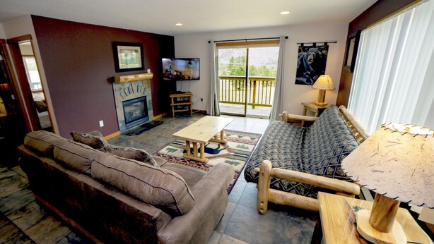 A living room with a sofa, a patterned armchair, a wooden coffee table, and a fireplace. - Rocky Mountain Retreat 1A- 4 bedroom/3 bath with personal hot tub offers Panoramic Mountain Views 4 Cabin (Estes Park)