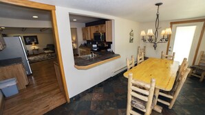 A kitchen with wooden cabinets, a built-in microwave, and a dining area with a wooden table and chairs. - Rocky Mountain Retreat 1A- 4 bedroom/3 bath with personal hot tub offers Panoramic Mountain Views 4 Cabin (Estes Park)