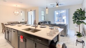 A modern kitchen with a central island, built-in appliances, and a dining area with a view of the outdoors.