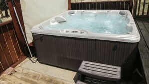 A hot tub on a wooden deck with a wooden bench and a chain for safety. - Rocky Mountain Retreat 2 Three Bedroom Cabin with Beautiful Views and Personal Hot Tub. 3 Cabin (Estes Park)