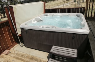 Un jacuzzi en una terraza de madera con un banco de madera y una cadena de seguridad.