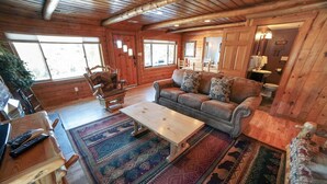 A cozy cabin interior with a wooden floor, a sofa, a coffee table, and a rug. - Rocky Mountain Retreat 2 Three Bedroom Cabin with Beautiful Views and Personal Hot Tub. 3 Cabin (Estes Park)