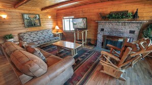 A cozy log cabin interior with a sofa, coffee table, and a fireplace. - Rocky Mountain Retreat 2 Three Bedroom Cabin with Beautiful Views and Personal Hot Tub. 3 Cabin (Estes Park)