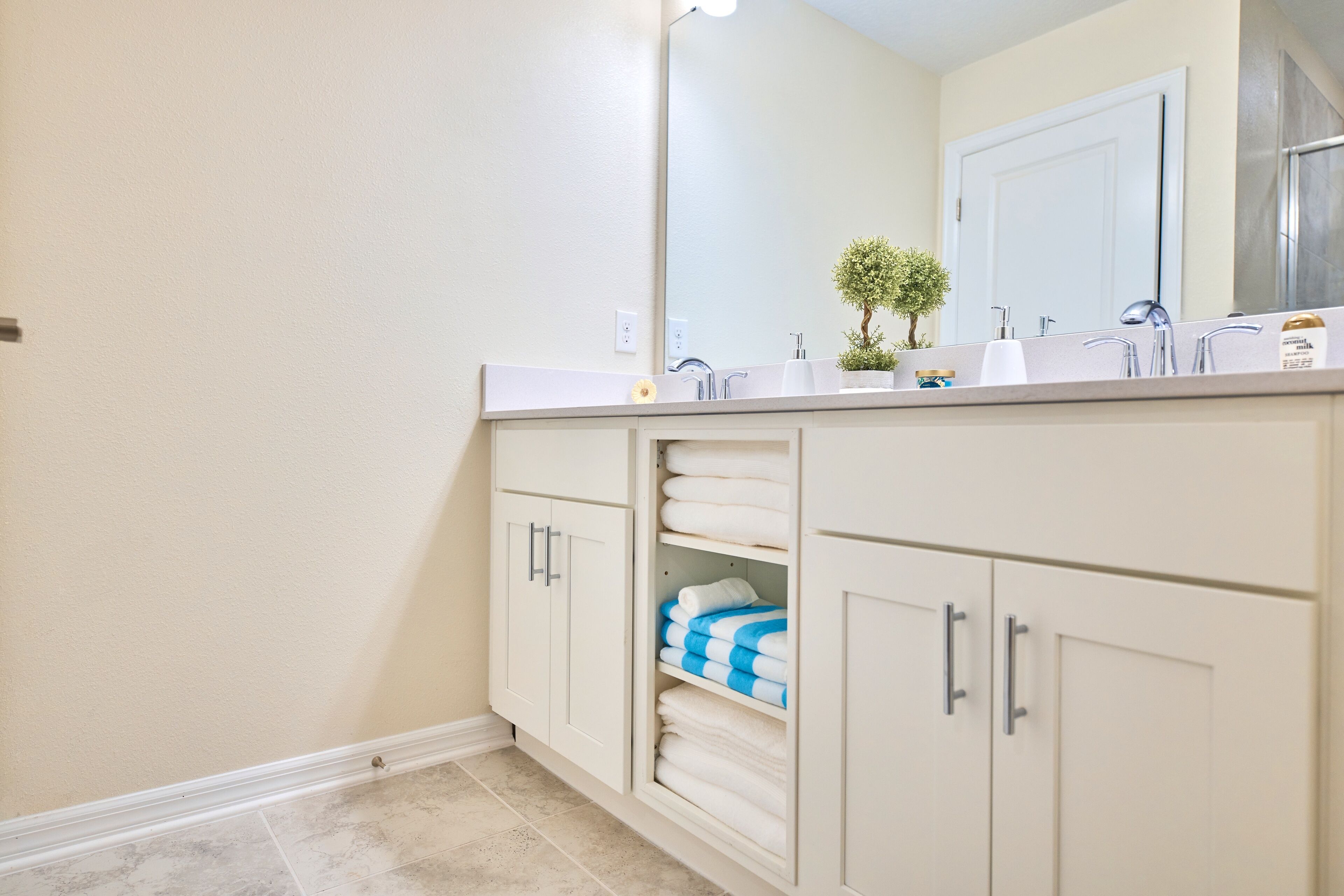 A bathroom with a white vanity, a mirror, a sink, and a towel rack.