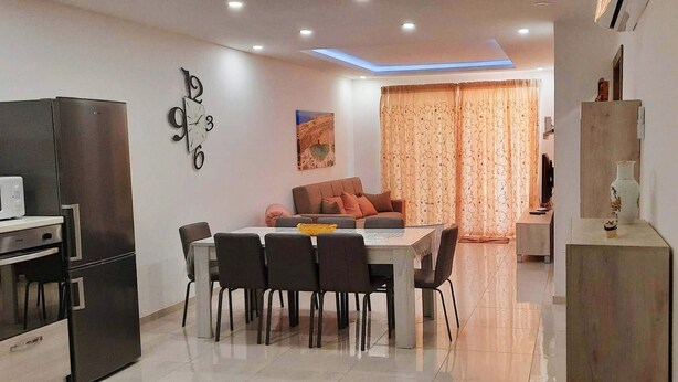 A modern kitchen with a dining area, a sofa, and a TV. - Beautiful 2 Bed Apartment in Għajnsielem (Ghajnsielem)