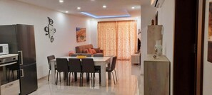A modern kitchen with a dining area, a sofa, and a TV. - Beautiful 2 Bed Apartment in Għajnsielem (Ghajnsielem)