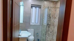 A modern bathroom with a toilet, sink, and shower area. - Beautiful 2 Bed Apartment in Għajnsielem (Ghajnsielem)