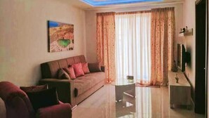 A modern living room with a sofa, a coffee table, and a flat-screen TV. - Beautiful 2 Bed Apartment in Għajnsielem (Ghajnsielem)