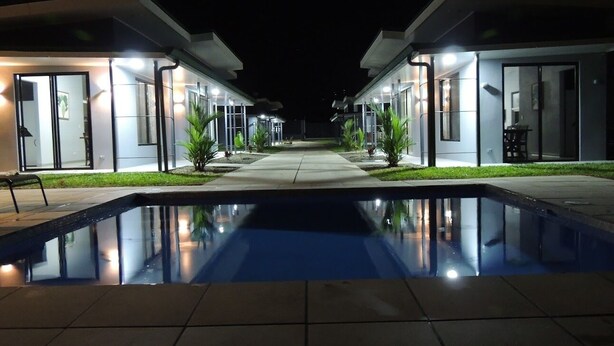 Um hotel moderno com piscina central, quartos bem iluminados e um design limpo e contemporâneo.