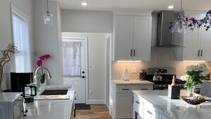 A modern kitchen with white cabinetry, a wooden floor, and a central island.
