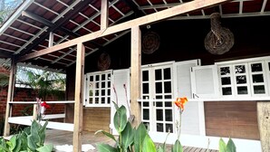 Un espacio al aire libre cubierto con estructura de madera, plantas en macetas y suelo de baldosas.
