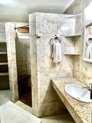 A bathroom with a marble wall, a sink with a faucet, and a towel hanging on a rack.