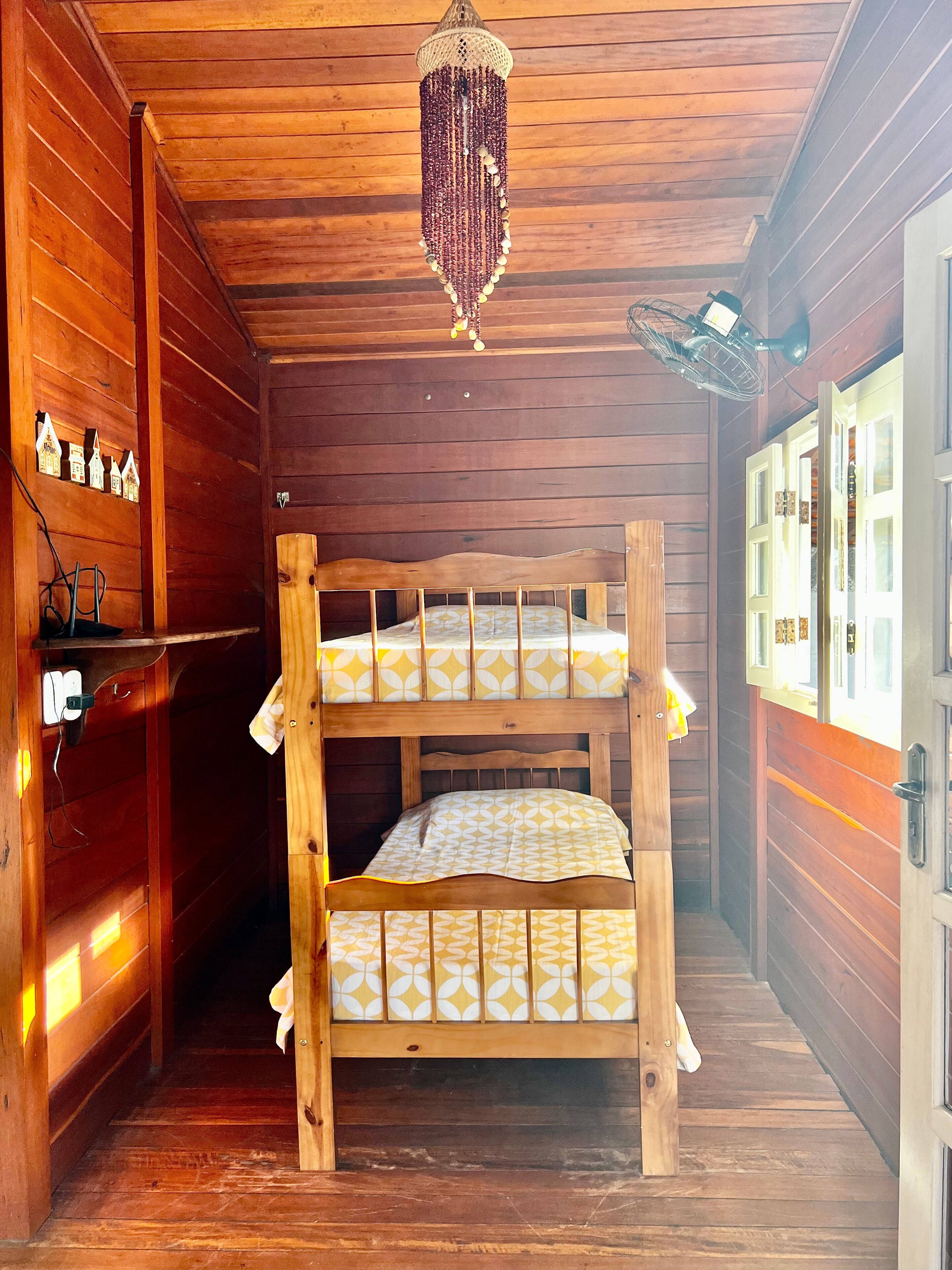 A wooden cabin room with bunk beds, a chandelier, and a fan.
