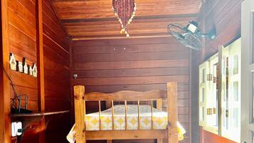 A wooden cabin room with bunk beds, a chandelier, and a fan.