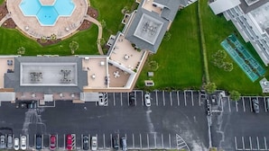 An aerial view of a hotel with a swimming pool, multiple parking spaces, and a tennis court. - Maria Beautiful Beachfront Condo, sleeps up to 8. BIG DISCOUNTS NOW  (Flagler Beach)