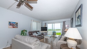 A living room with a sofa, armchairs, a coffee table, a TV, and a view of the outdoors. - Maria Beautiful Beachfront Condo, sleeps up to 8. BIG DISCOUNTS NOW  (Flagler Beach)