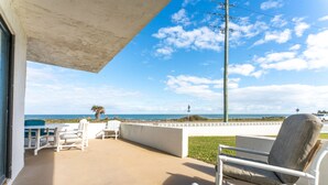 A patio with outdoor seating, a view of the ocean, and a clear sky. - Maria Beautiful Beachfront Condo, sleeps up to 8. BIG DISCOUNTS NOW  (Flagler Beach)
