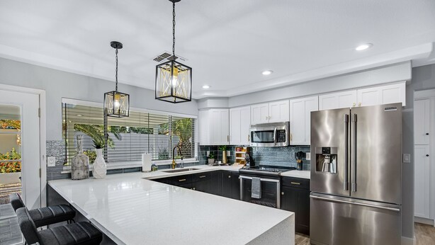 A modern kitchen with a large island, stainless steel appliances, and a hanging light fixture. - Minutes from Shopping, Dining & Golf (Scottsdale)