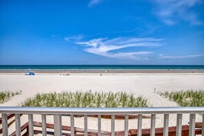 A beach with a clear sky, a sandy shore, and a few umbrellas. - Ground Floor Beachfront 2BR with Direct Pool and Car Free Beach Access (New Smyrna Beach)