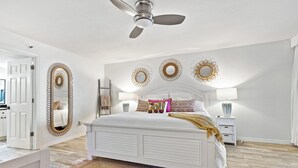 Un dormitorio con una cama, un ventilador de techo y espejos decorativos en las paredes.