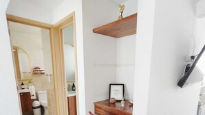 Un interior moderno con un escritorio de madera, una silla roja y un televisor blanco montado en la pared.